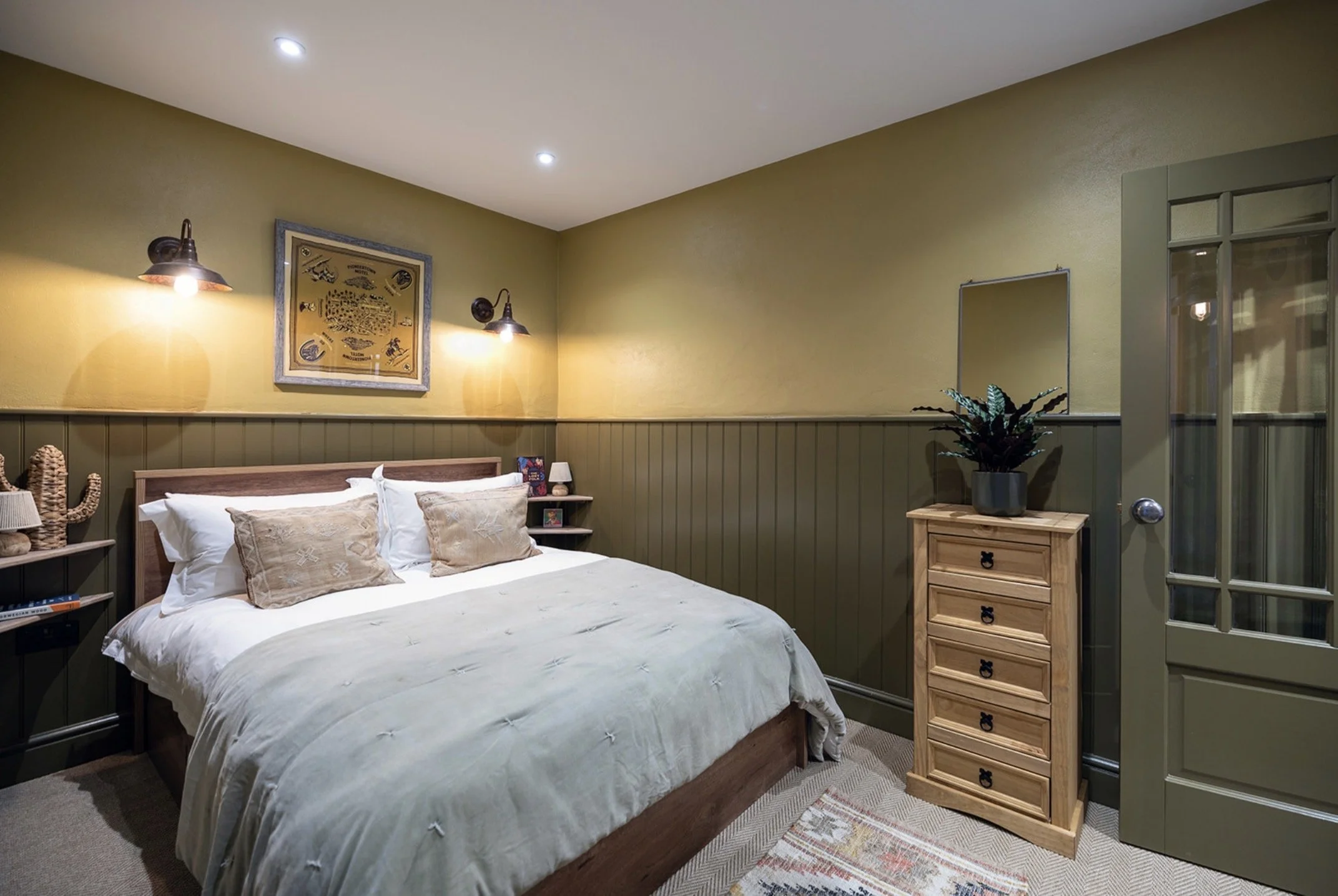 A double bedroom with green painted walls and panelling to the lower half.