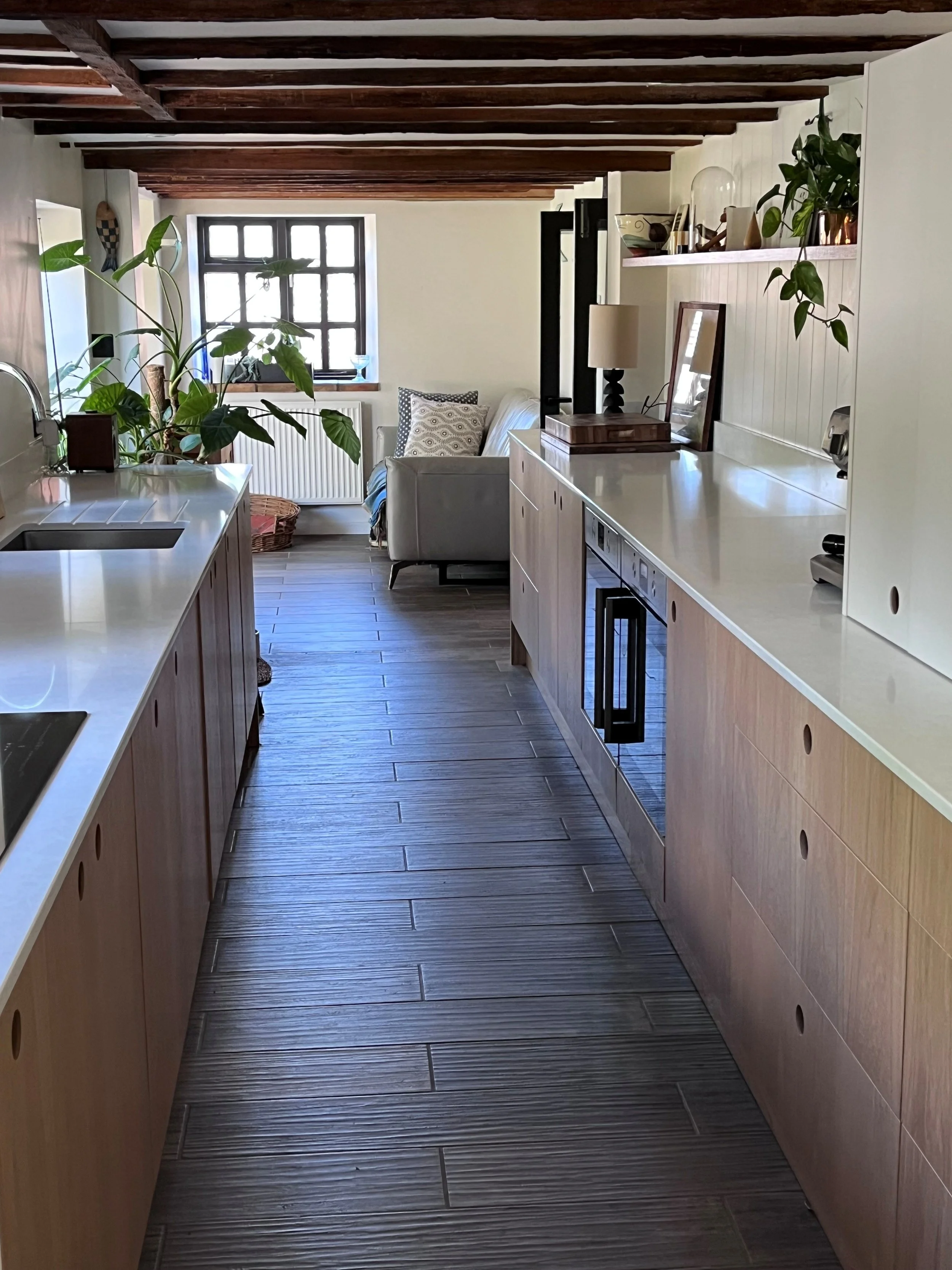 Modern galley kitchen showing the property period beams, wood floor and stone worktops