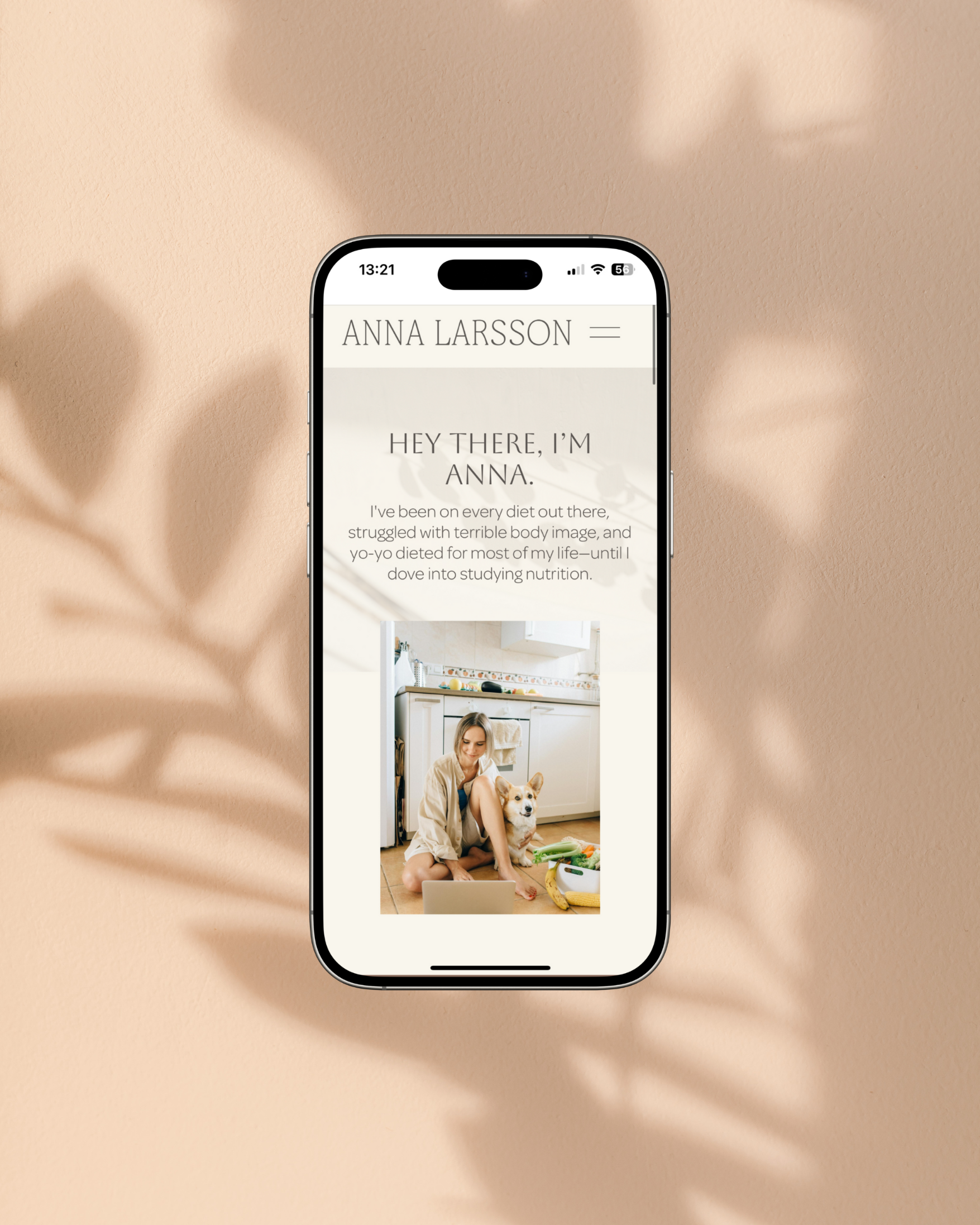 Smartphone displaying a website with the name Anna Larsson, showing a picture of a woman with a dog in a kitchen.