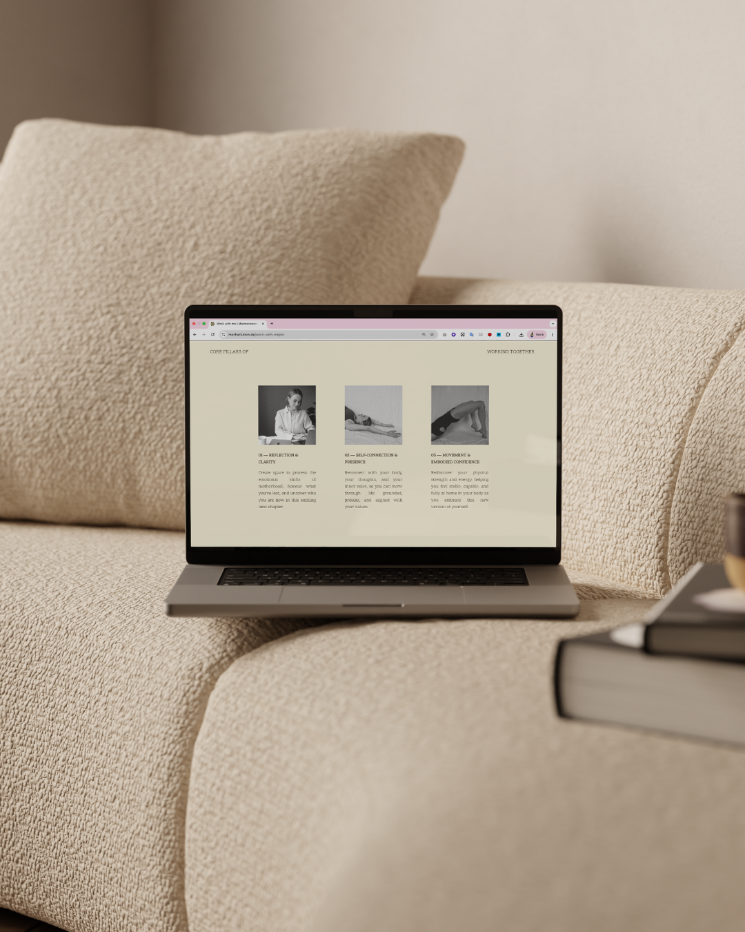 Open laptop on beige sofa displaying a wellness or yoga website, next to closed books.