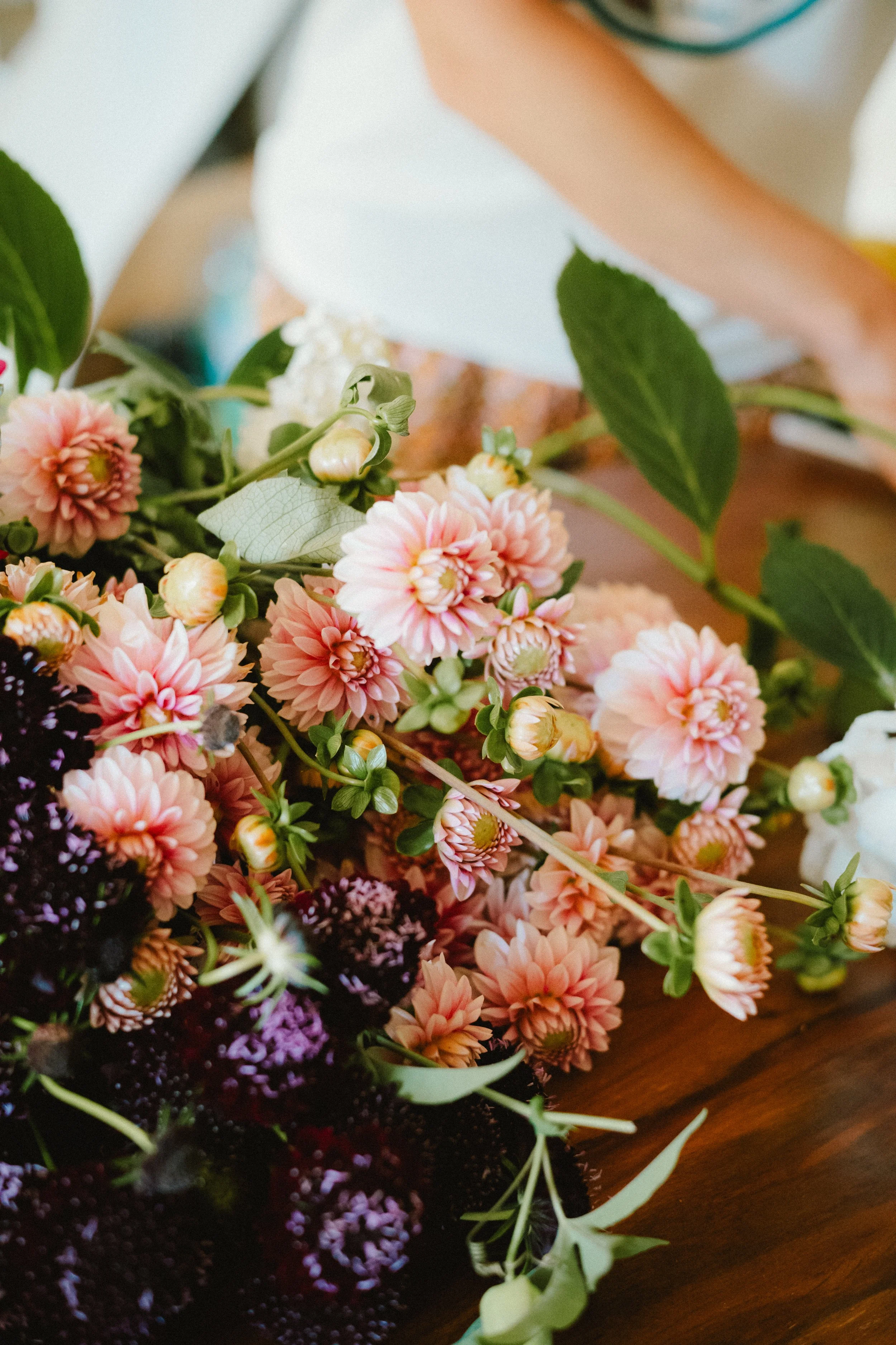 Un bouquet de fleurs roses, blanches et sombres repose sur une surface en bois.