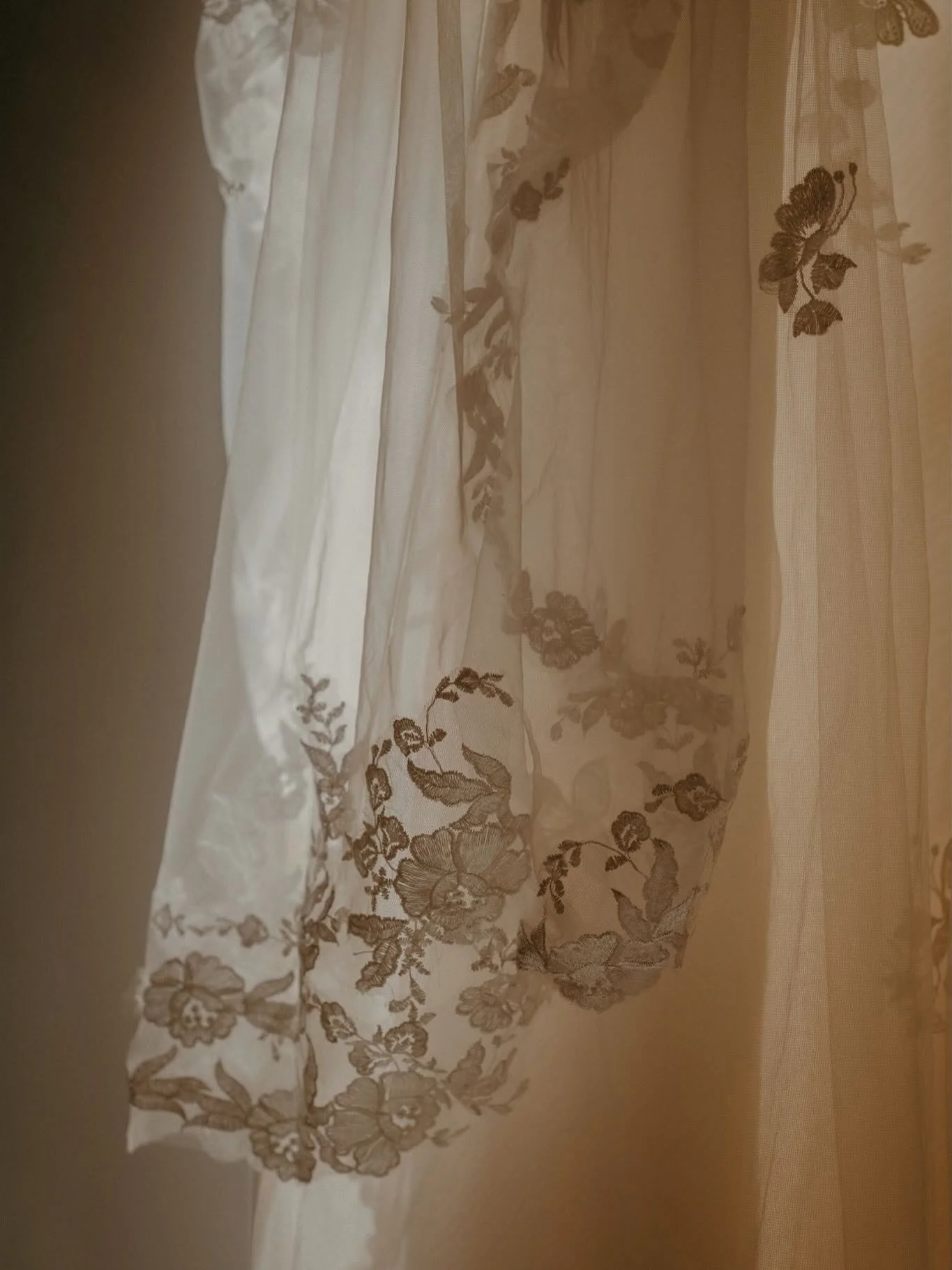 Close-up of a white lace curtain with floral embroidery.