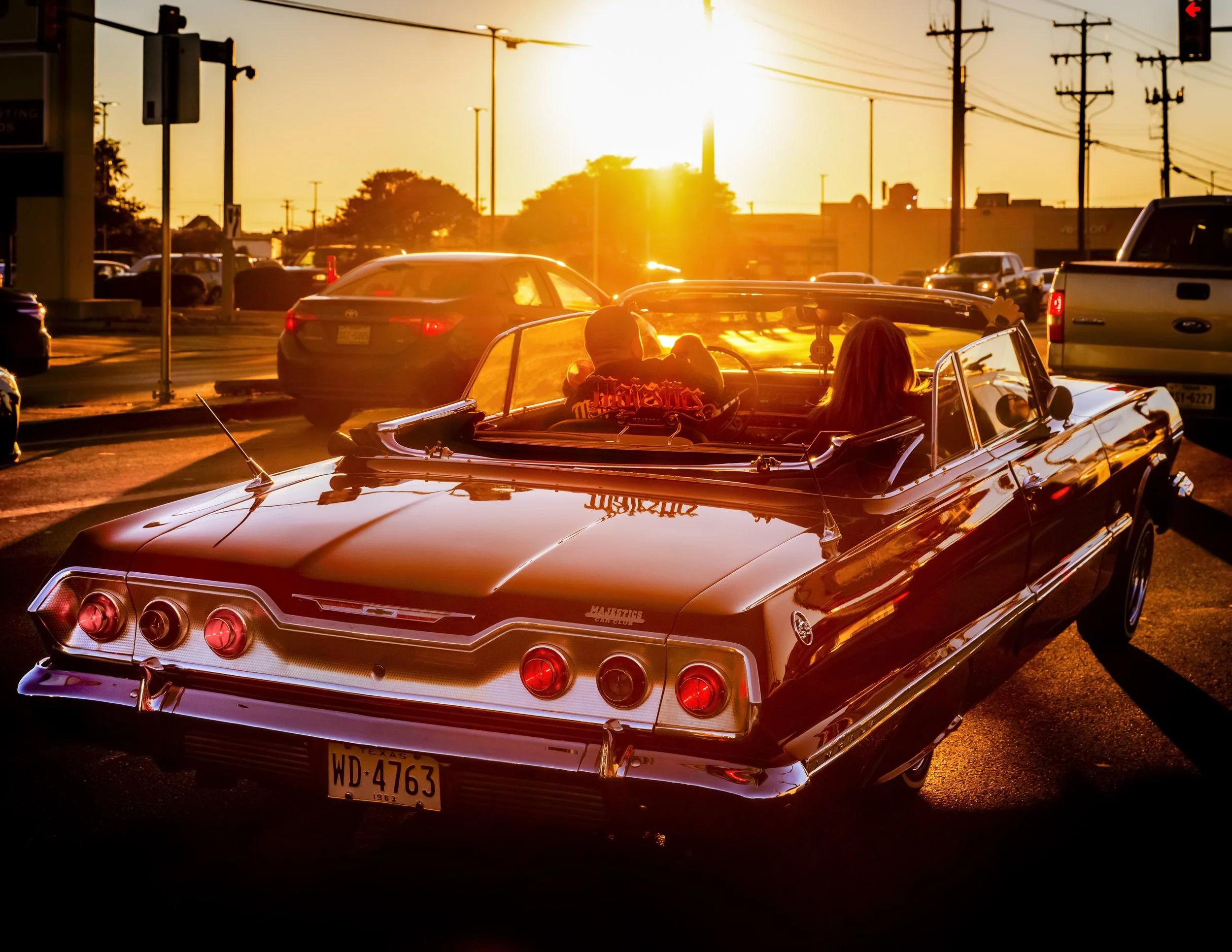 Al Rendon, "Sunset Cruise, Angel Morales and wife in their 1964 Convertible Impala Lowrider, SW Military Drive, San Antonio, Texas, Jan. 2024." ©2026 Al Rendon.