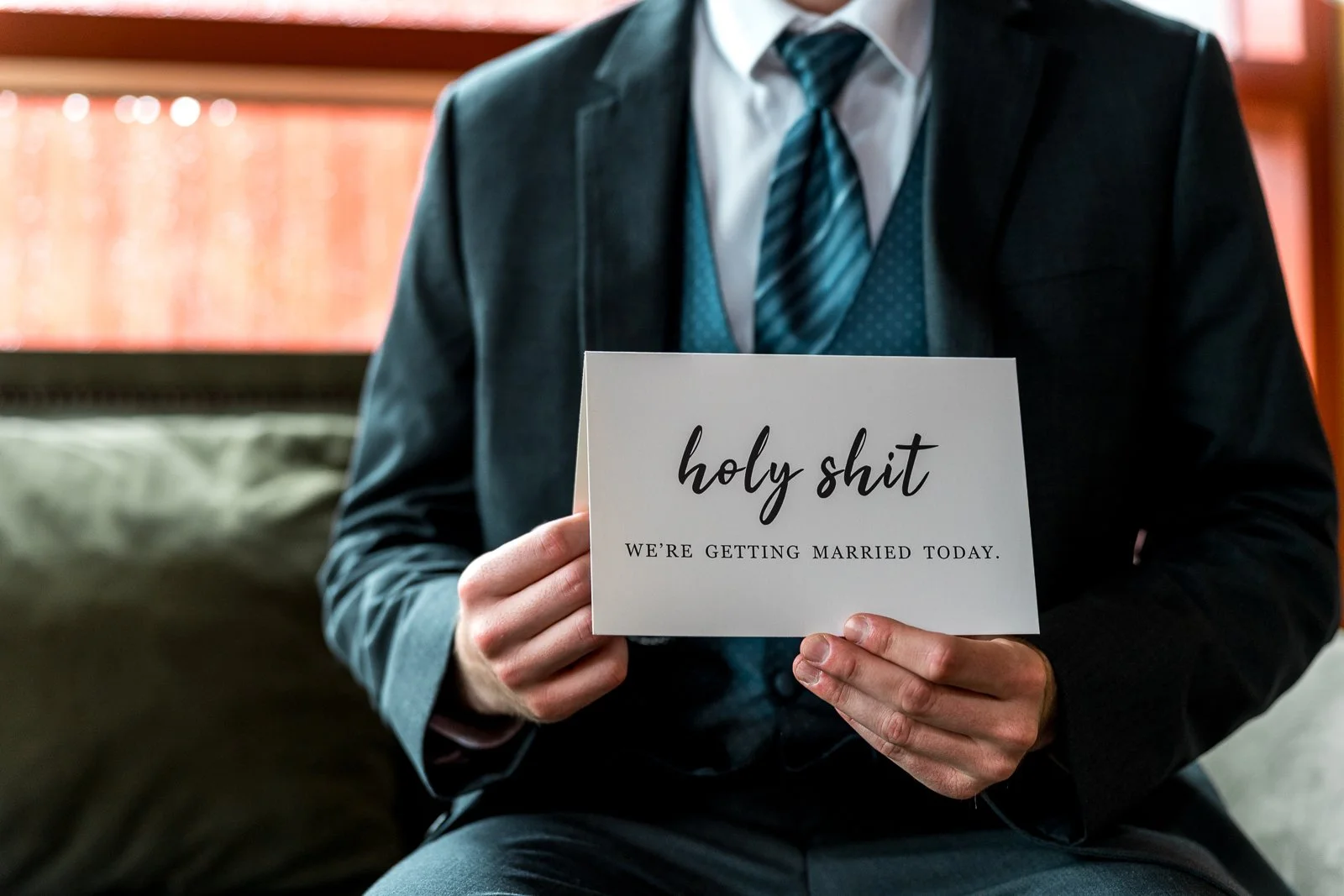 Person in a suit holding a card that says "holy shit we're getting married today"