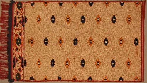 Bulgaria. Sliven. Apron in cotton and Silk. Dimensions 97 x 54 cm. Plain and twill weave with embroidery.  The ground is made from red tabby woven cotton cloth, which is almost completely covered with a cream-coloured diamond twill pattern. This is e