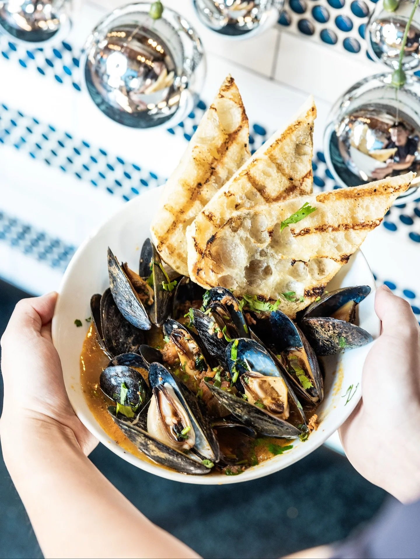 A bowl that does it all: tender Prince Edward Island mussels bathed in a champagne sofrito chorizo cilantro broth &mdash; rich, fragrant, and just the right amount of heat.