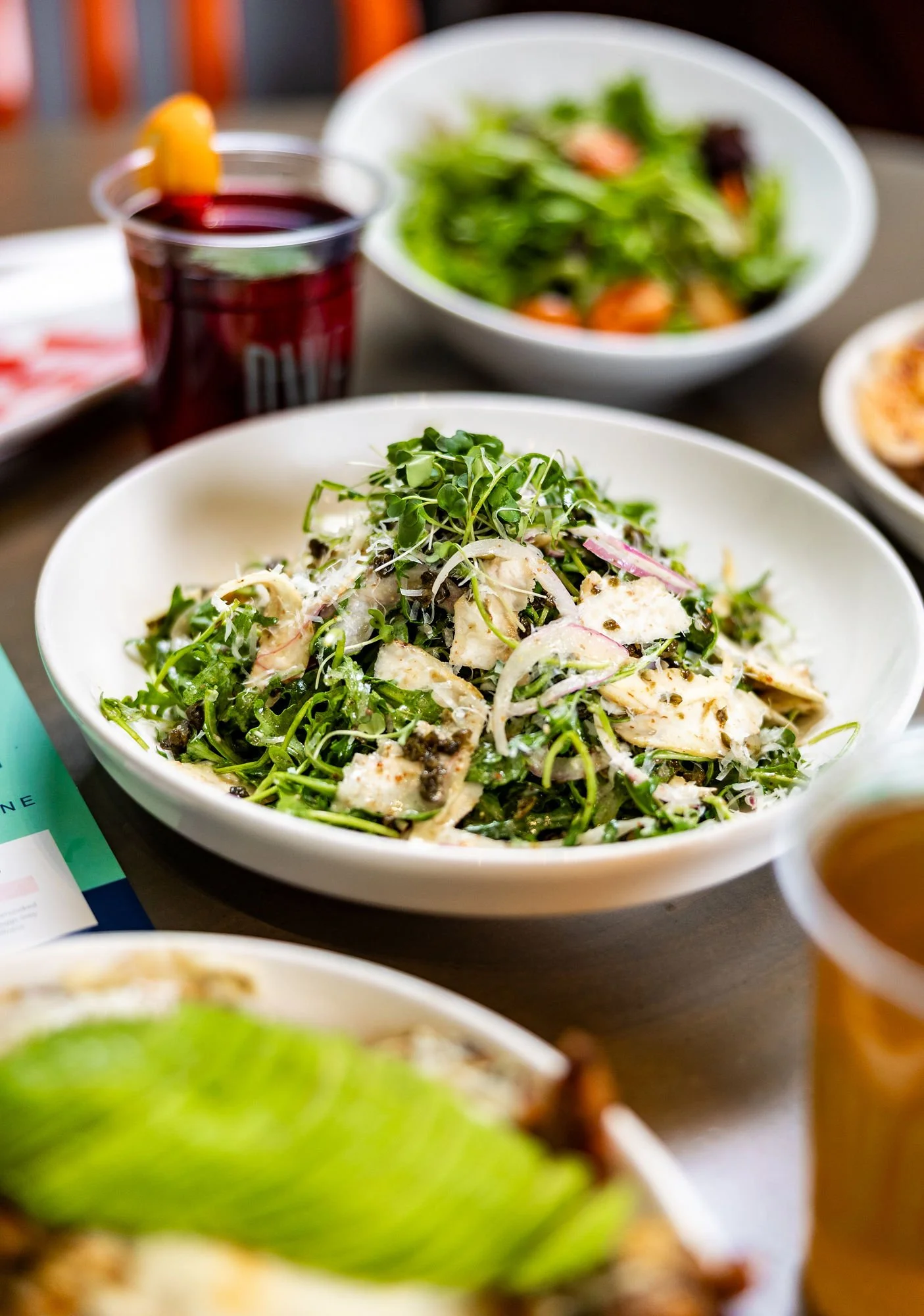 Fresh chopped chicken salad topped with grilled chicken pieces on a white square plate.