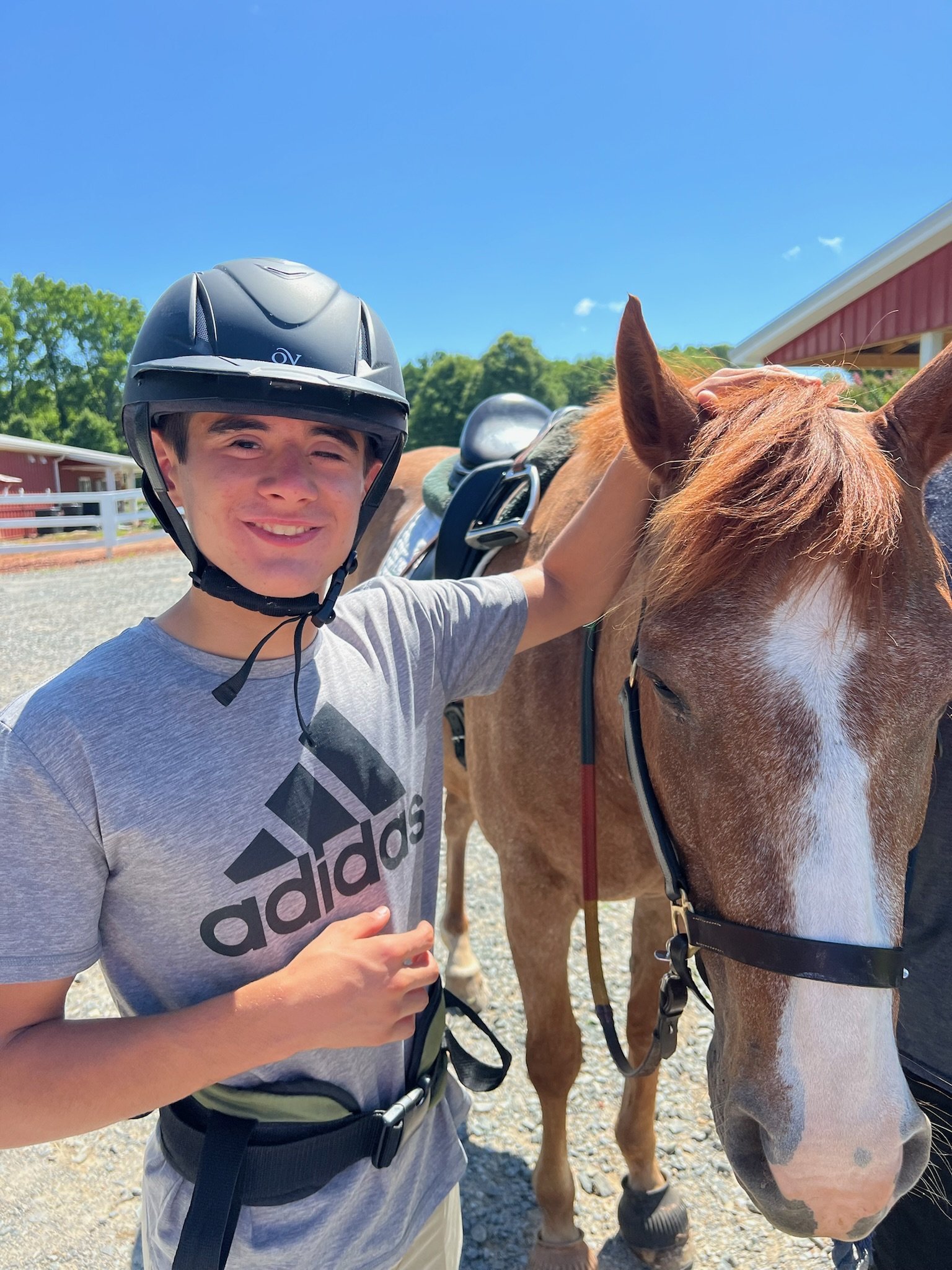 A smiling Bravo Camper standing next to a horse