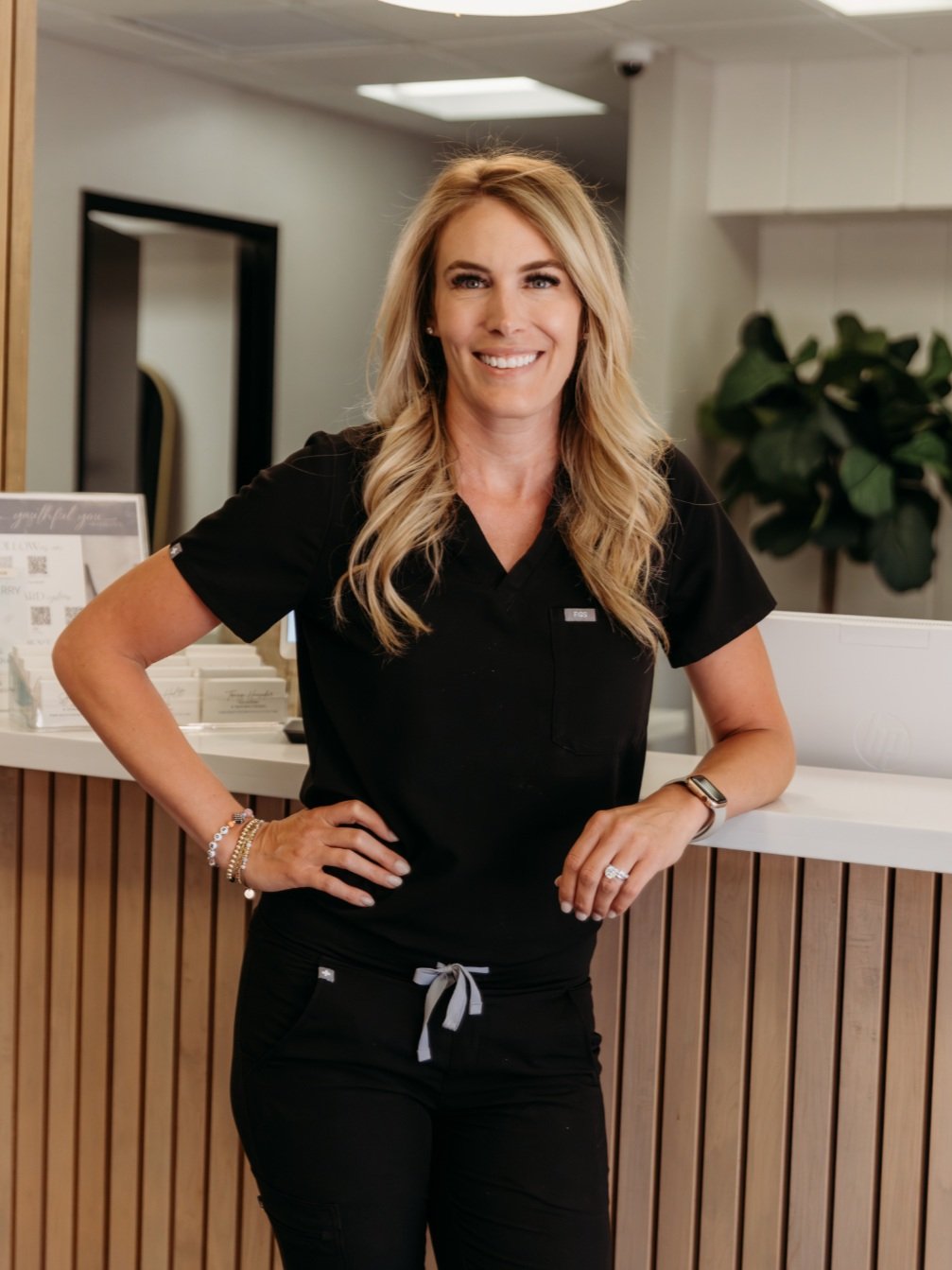 Professional woman in black scrubs leaning on her front desk