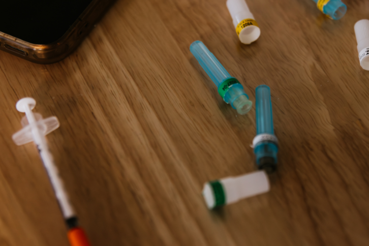 Close-up of vitamin injection syringes and medical tubing on a wooden table, representing IV therapy and wellness services
