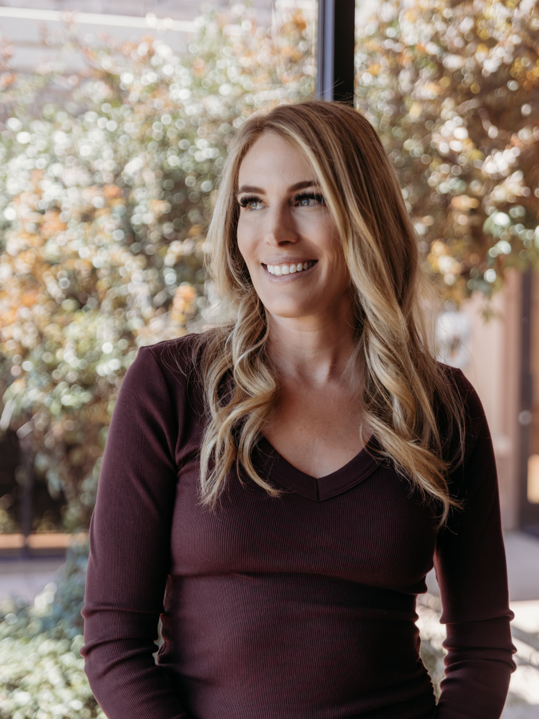 Lisa, RN wearing a maroon dress at her cosmetic injectable office in Peoria, AZ
