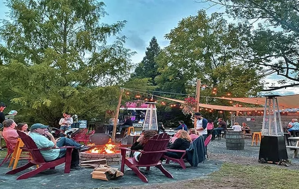 People sit around a fire pit in Adirondack chairs at Shawnee Craft Beer Garden