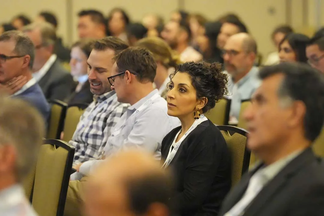 A diverse group of people sitting in an audience at a conference, listening attentively and engaged.