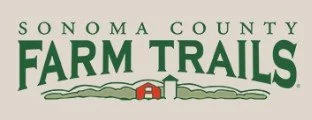 Logo for Sonoma County Farm Trails with green text and a small red barn illustration