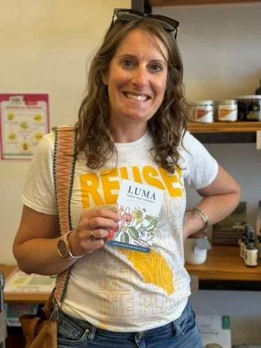 image of woman standing in store holding Luma Front Yard Farming card