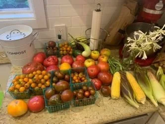 baskets of tomatoes and veggies on a kitchen counter