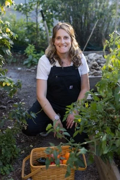 Woman in overalls in the garden with a basket of vegetables