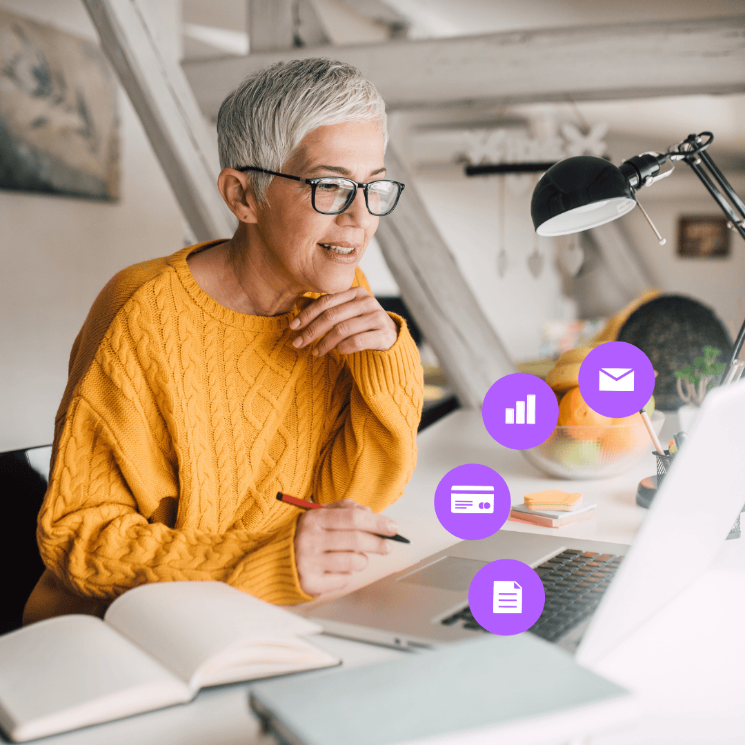 Woman in an orange sweatshirt using GoodCRM features on a laptop