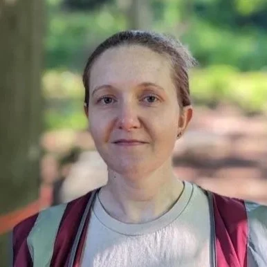 Woman outdoors with green trees in the background