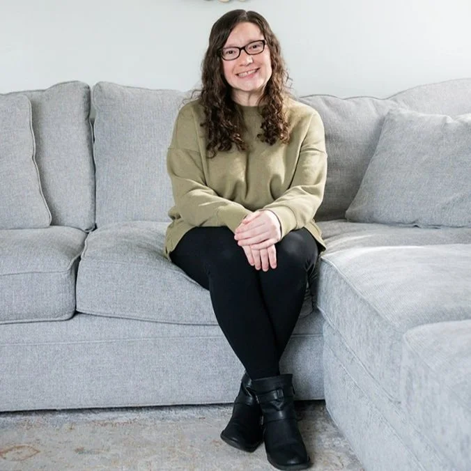 Therapist at B&B Well counseling sitting on a couch smiling warmly, representing supportive care in therapy for anxious perfectionists in Bay Shore, New York.