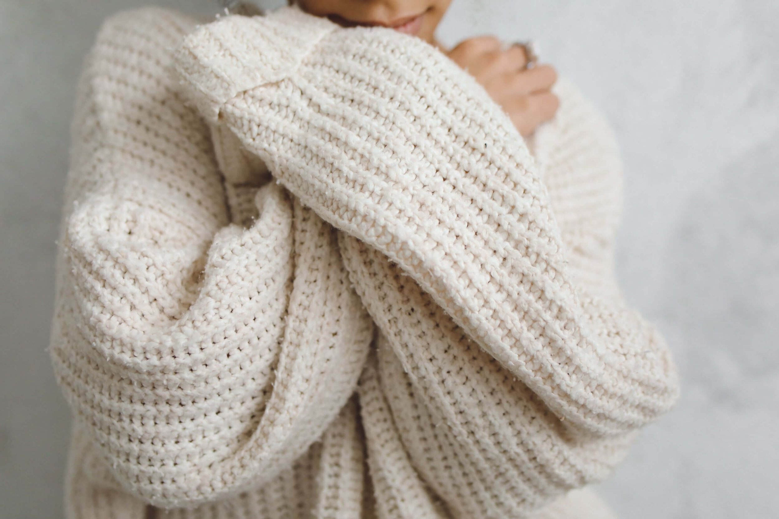 Close-up of a person hugging themselves while wearing a sweater, representing emotional healing, self-care, and rebuilding identity through therapy for losing yourself in a relationship in Bay Shore, NY.