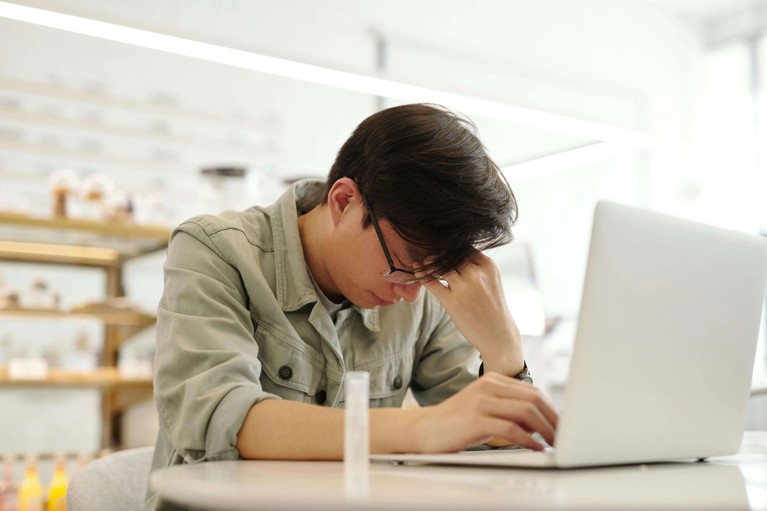 Young adult man on a laptop with hand on forehead, illustrating stress related to family boundaries addressed in setting boundaries with family in Bay Shore, NY.