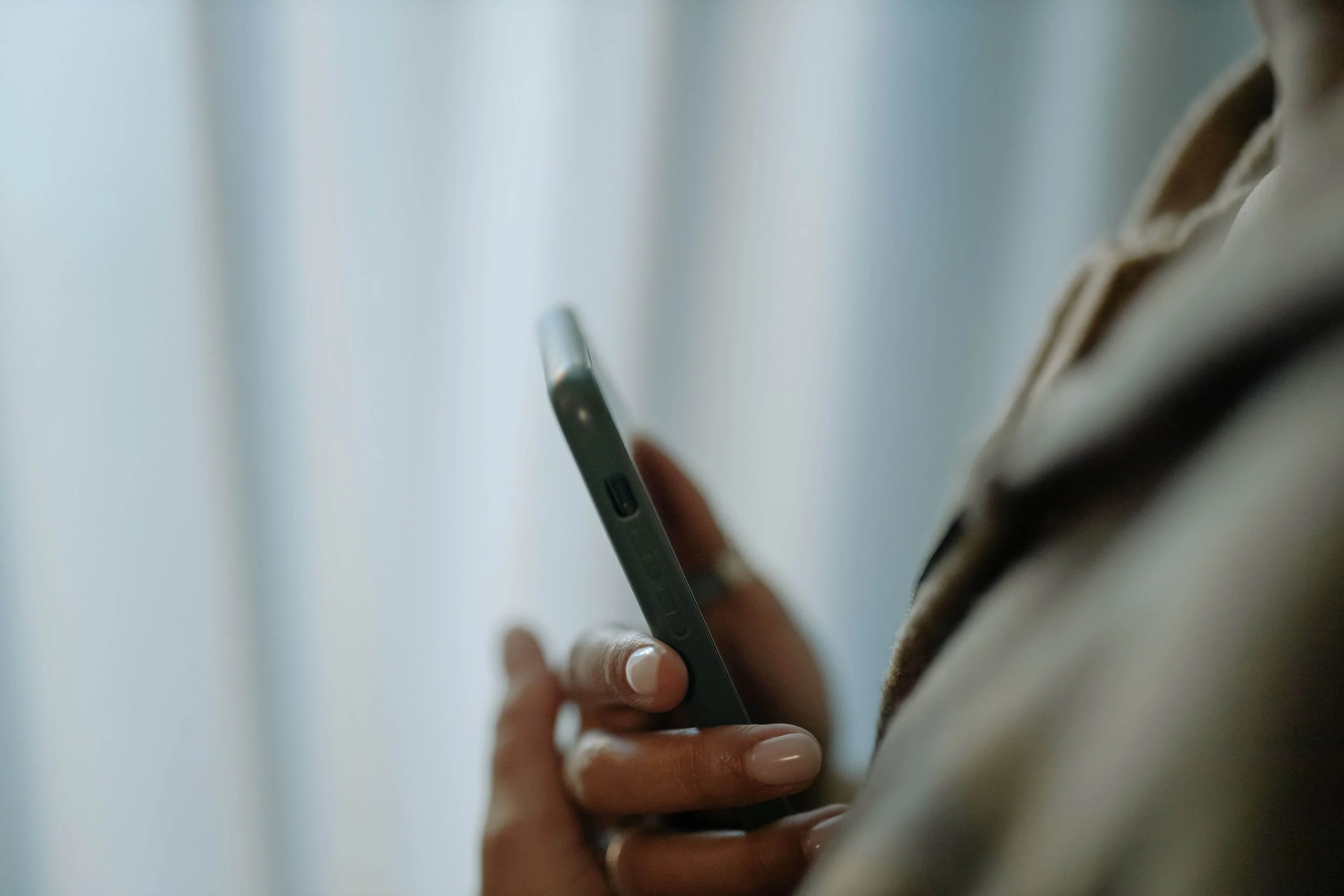 Close-up of someone holding a smartphone, representing the pressure of always being available explored through boundaries therapy for young adults in Bay Shore, NY.