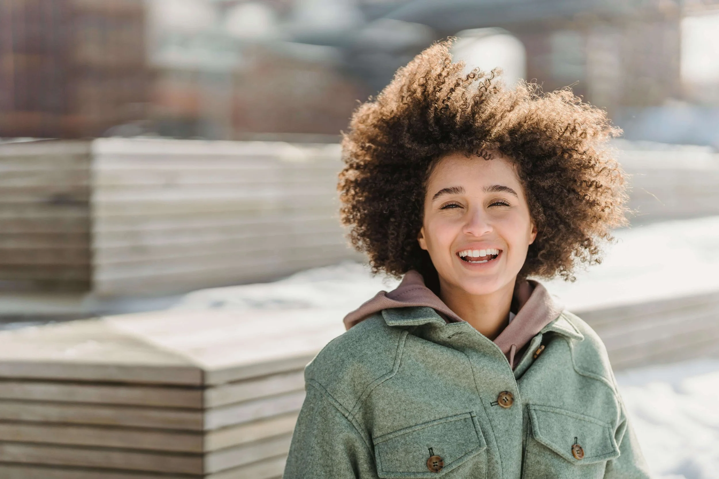 Woman with curly hair smiling outdoors, symbolizing healing and progress through therapy for anxious perfectionists in Bay Shore, New York.