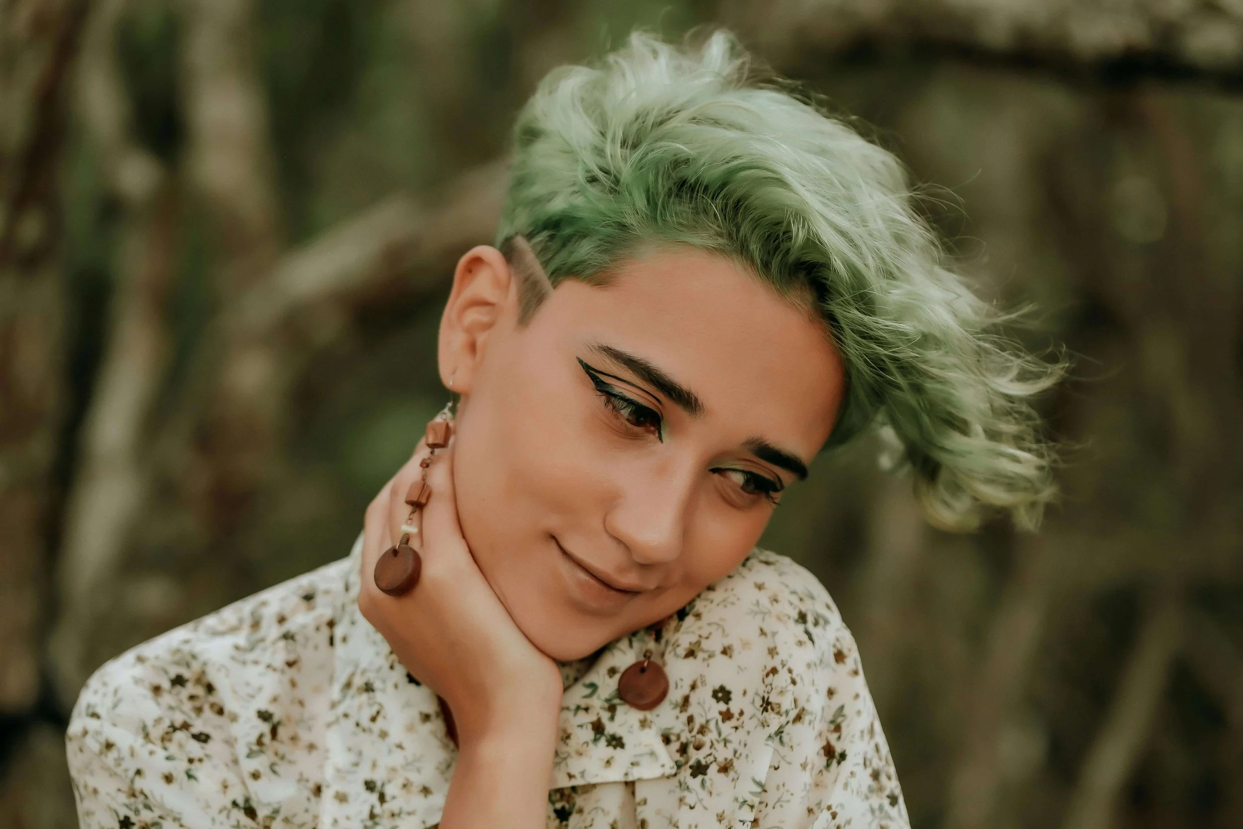 Close-up of a person with artistic makeup and green hair, symbolizing identity exploration and self-expression in young adult therapy for navigating identity in Bay Shore, NY.