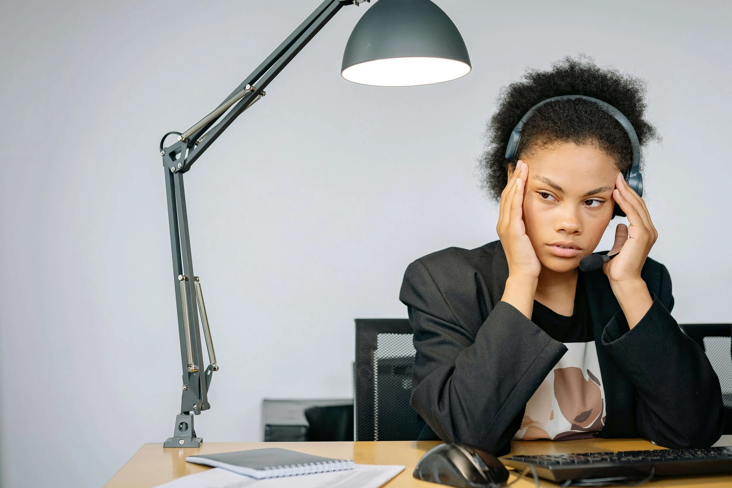 Young woman at work looking stressed, reflecting challenges addressed in perfectionism therapy for young adults in Bay Shore, NY.