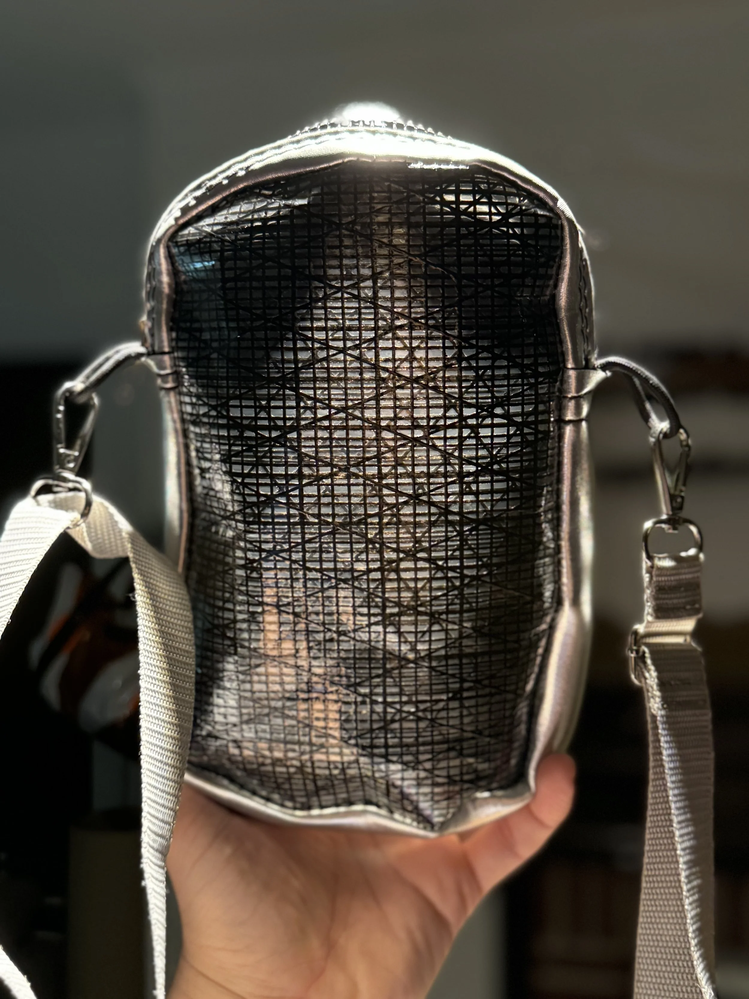View inside an empty small backpack showing black mesh interior and beige straps, held by hand.