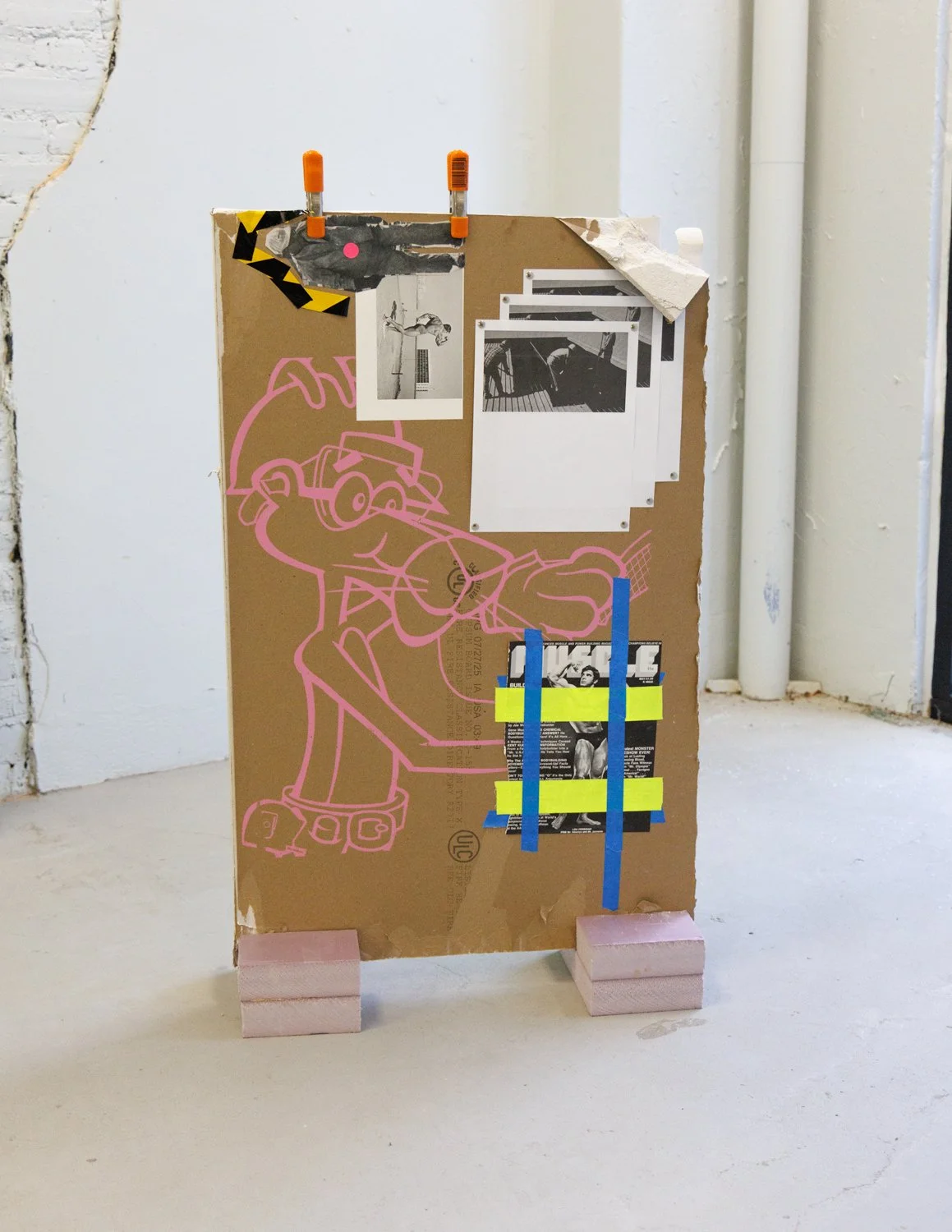 Mr. Universe (2025) (view 1) drywall, ink, found images, inkjet prints, gaffers tape, painters tape, cellophane tape, caution tape,  thumb tacks, Carhartt Hi-Vis long-sleeved shirt, polystyrene insulation foam, and clamps