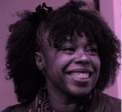 Close-up of a smiling woman with natural curly hair and earrings, in front of a purple background.