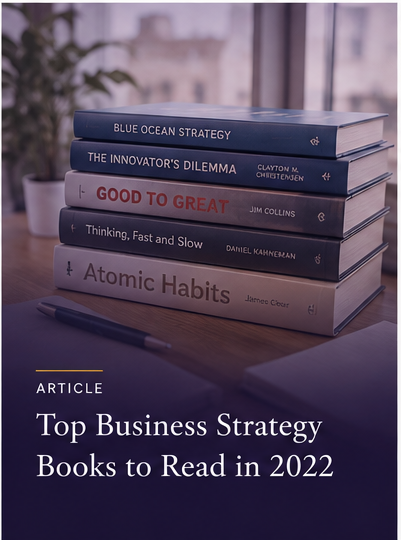 Stack of six business strategy books on a desk with a pen in front, window in background.