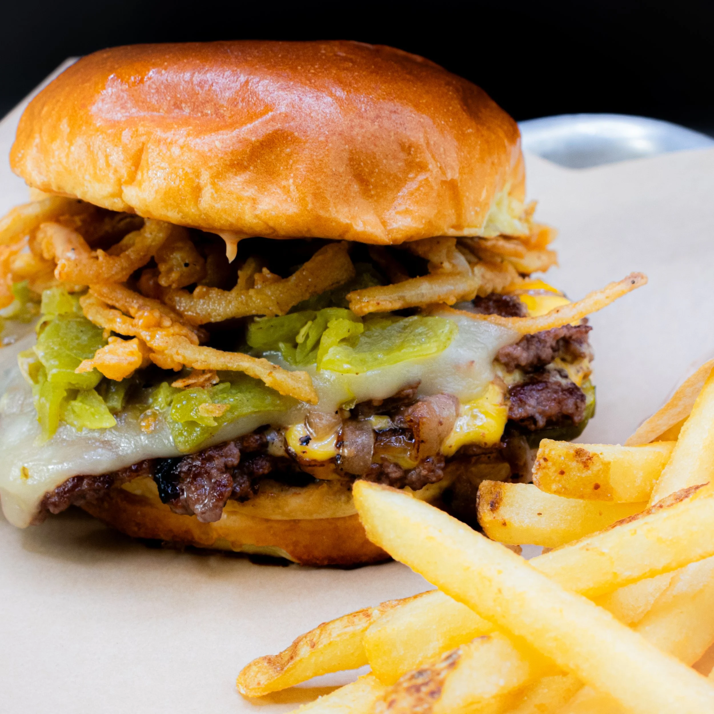 Fiamma Burger Hatch Chile Burger with Hatch Chiles, triple cheese, crispy fried onions and Fiamma sauce on buttery buns.