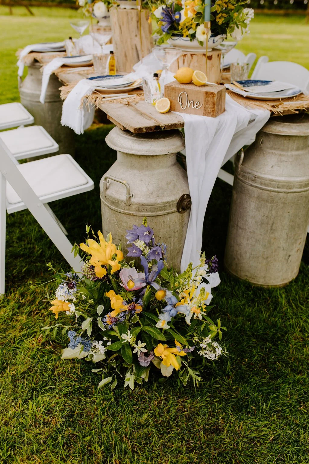 Milk churns as table legs on an outdoor dining table for weddings - Mae & Maple Prop & Decor Hire