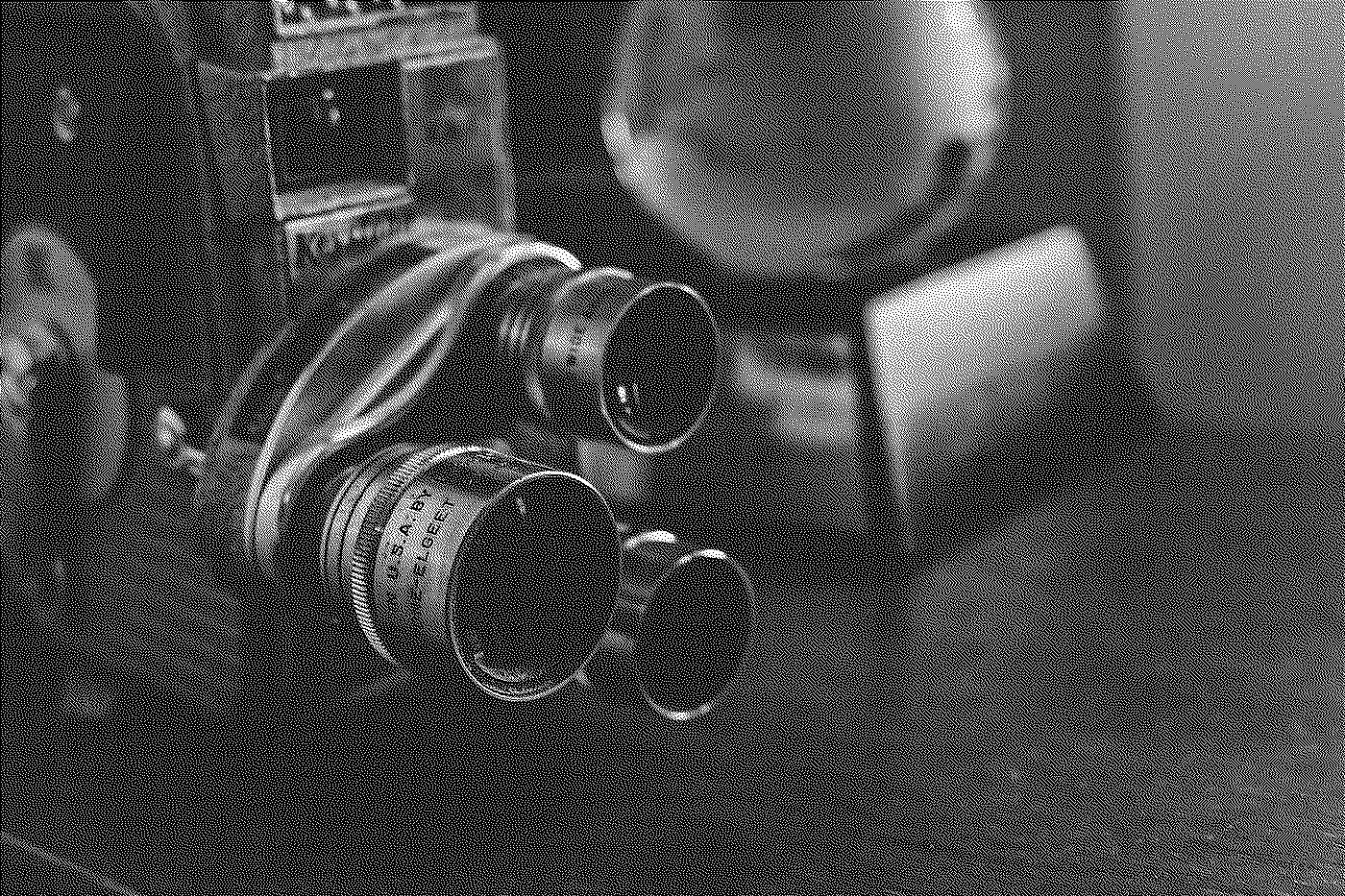 Black and white photo of a vintage camera, with a large lens and a boxy body, held by a person with glasses, face near the camera.