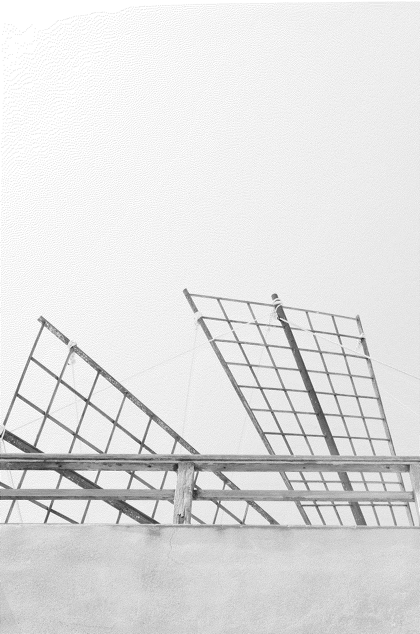 Two man-made solar panels or billboard structures tilted at an angle on a rooftop under a cloudy sky.