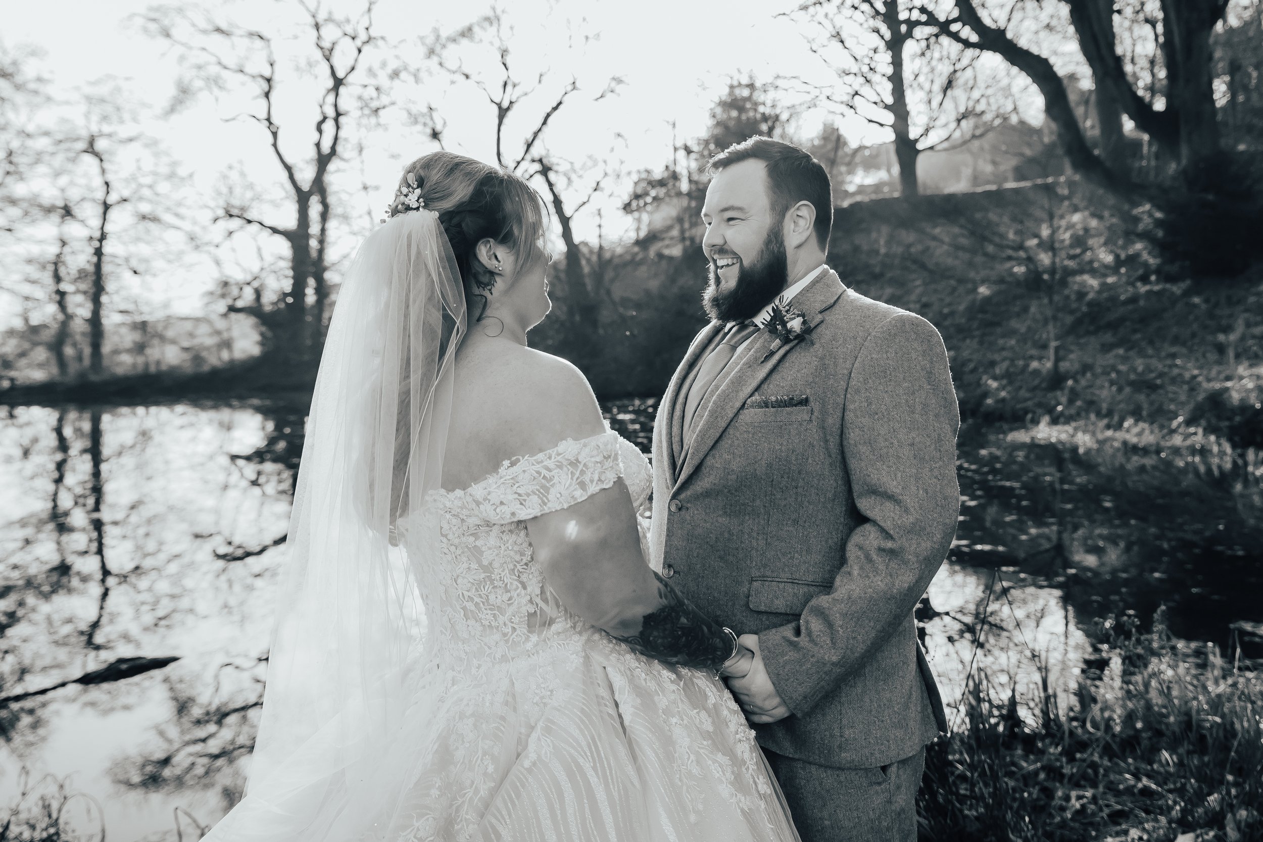 Bride and groom smiling at each other during an outdoor wedding.