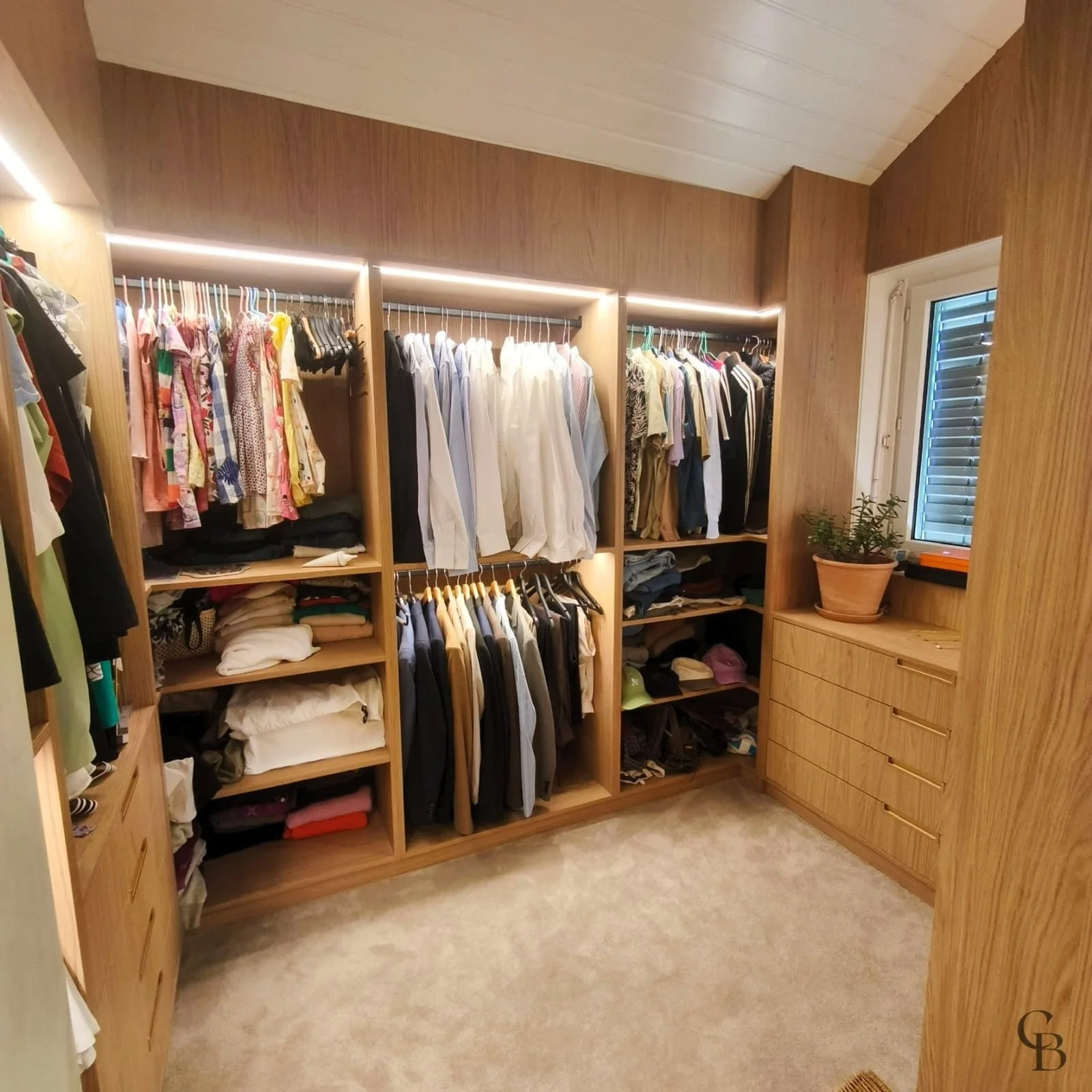Vue d'ensemble d'un dressing ouvert sur mesure avec penderies, étagères, mobilier intégré et éclairage LED, réalisé par Concept & Bois dans une villa à Nyon.