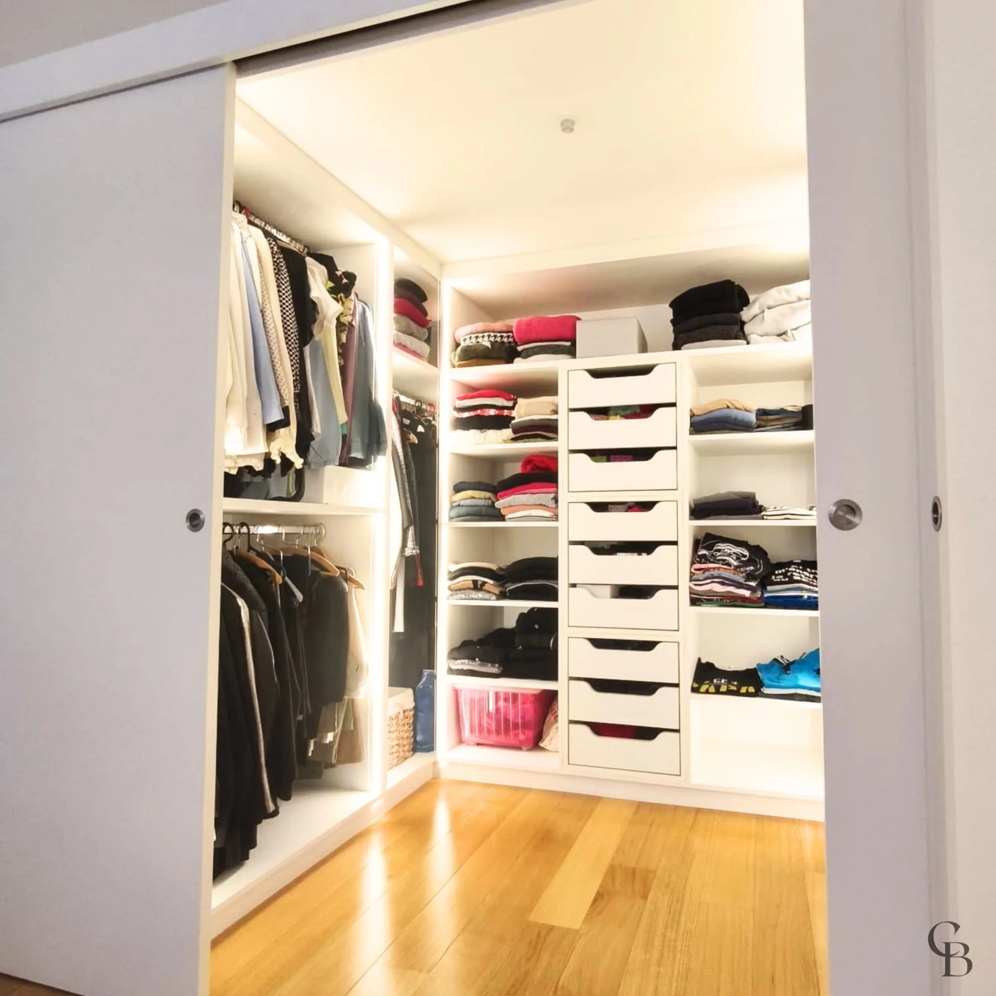 Ouverture des portes coulissantes révélant un dressing sur mesure entièrement aménagé.