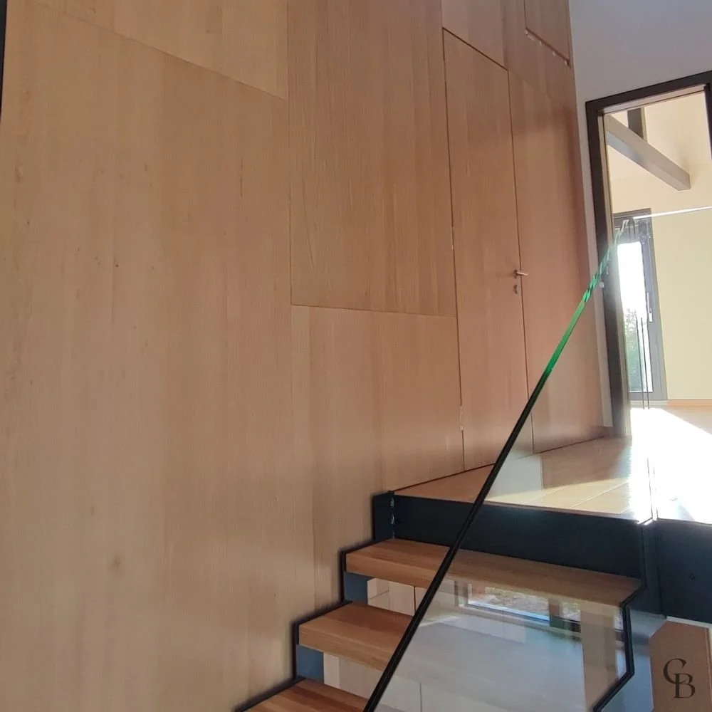Porte invisible intégrée dans un habillage mural en chêne, associée à un agencement intérieur sur mesure qui allie esthétique contemporaine, fonctionnalité et précision artisanale.