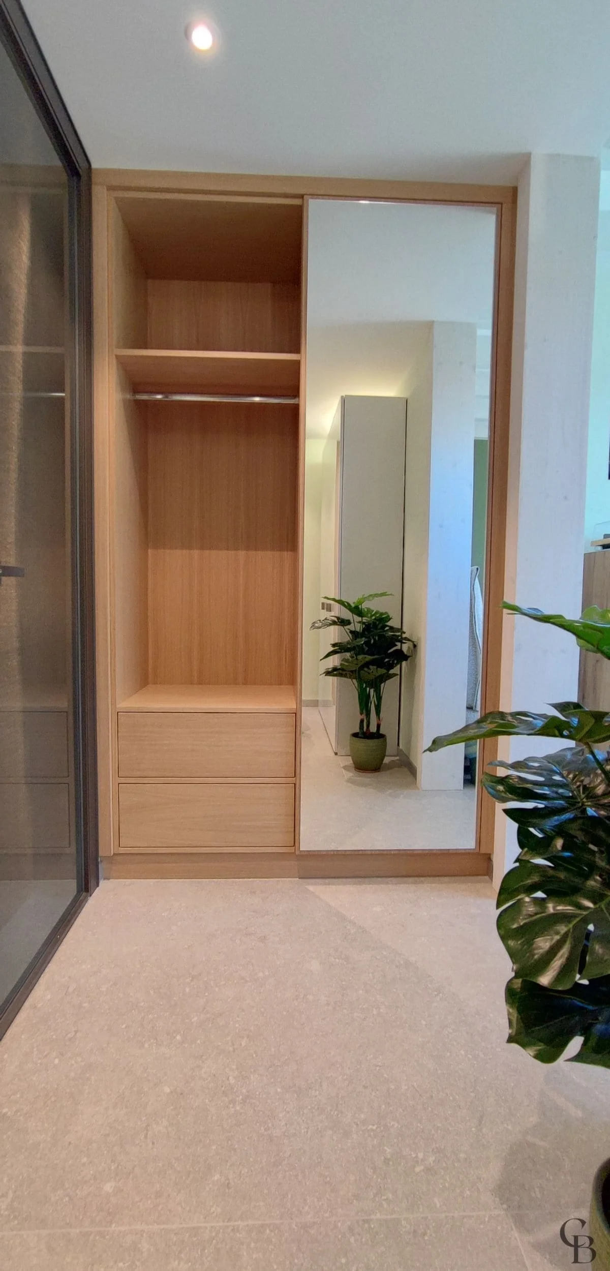 Armoire de rangement sur mesure avec porte miroir intégrée, conçue pour apporter luminosité et fonctionnalité à l'entrée.