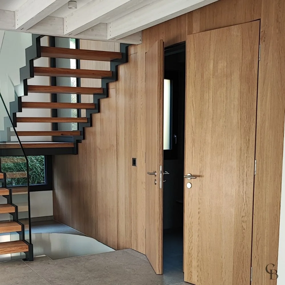 Agencement intérieur sur mesure avec habillage mural en chêne, portes invisibles intégrées et finitions haut de gamme, conçu pour créer un espace harmonieux et élégant.