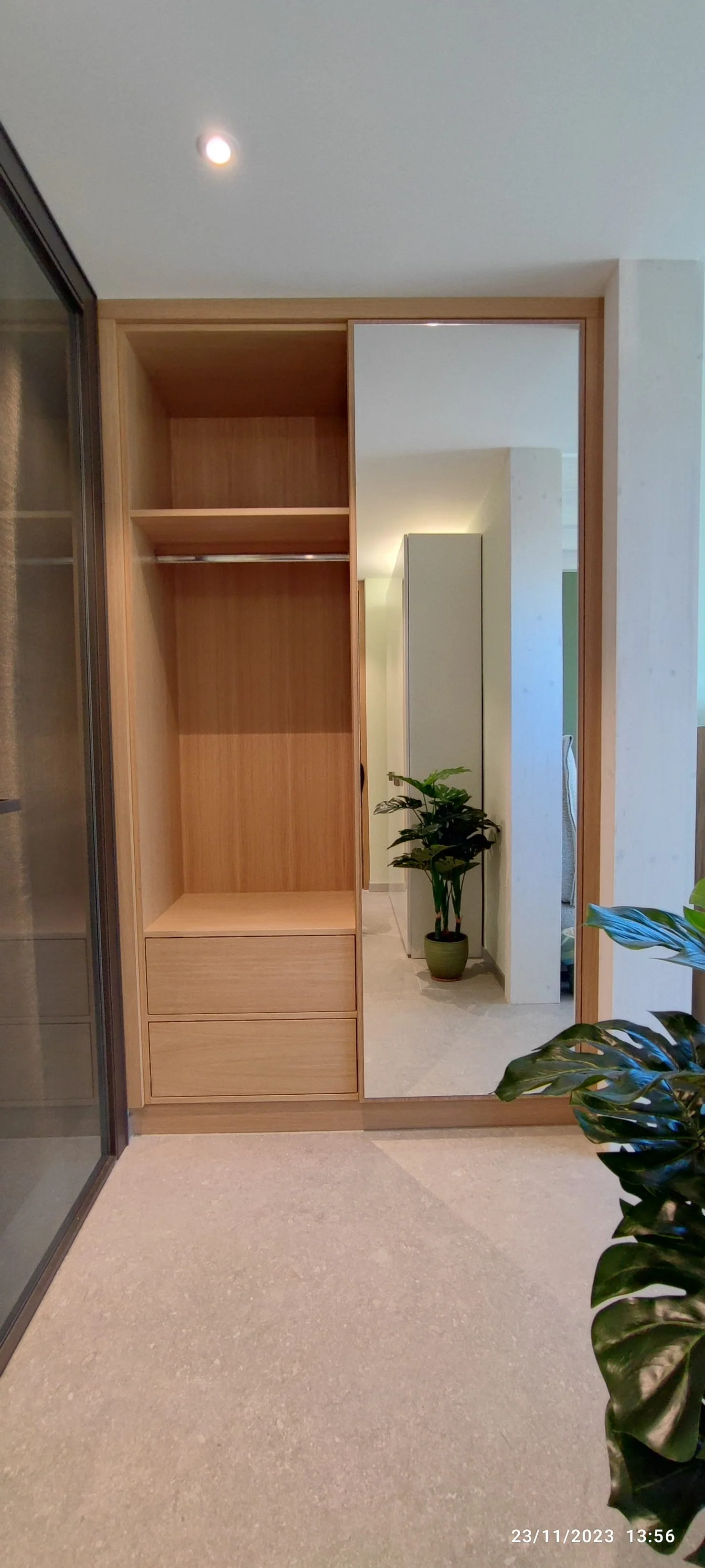 Armoire sur mesure en chêne avec miroir intégré et rangements personnalisés, conçue pour optimiser un petit espace à Trélex dans le canton de Vaud.
