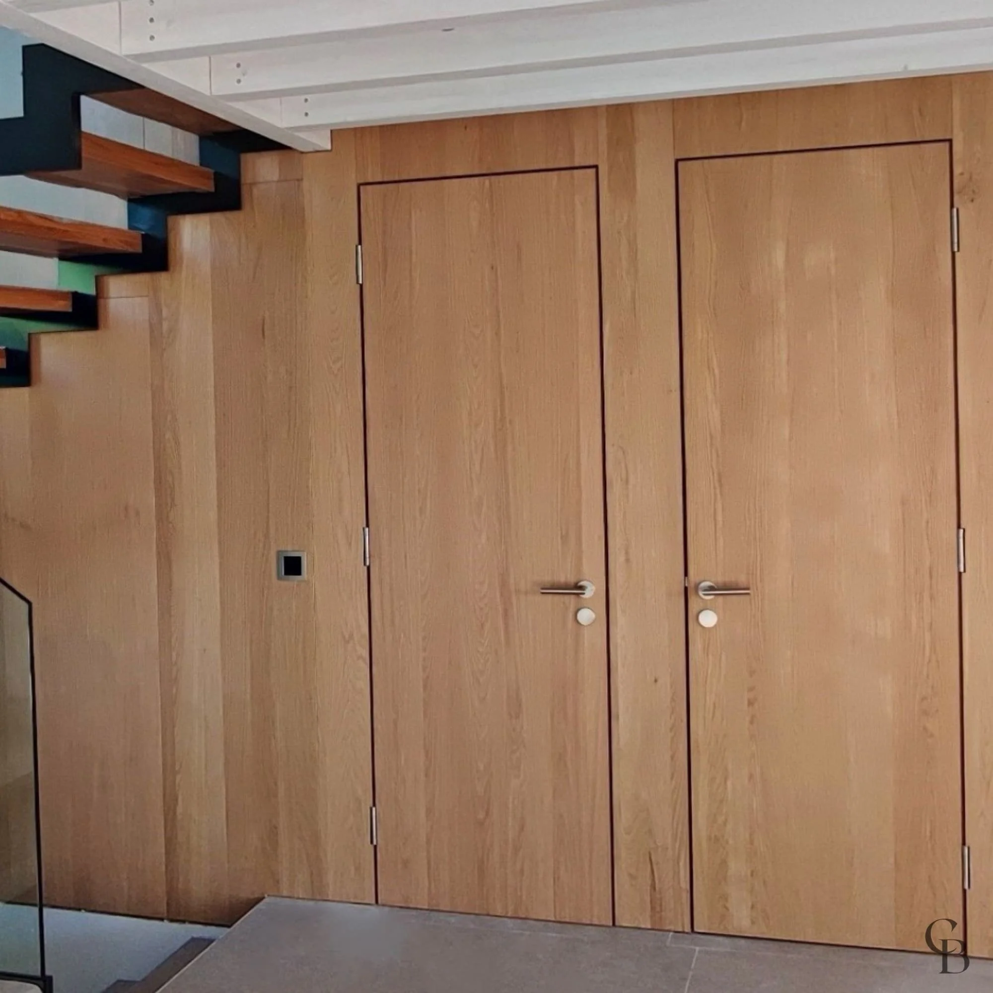 Habillage mural en chêne avec portes invisibles intégrées, réalisé sur mesure pour créer un espace épuré, élégant et parfaitement harmonisé avec l'architecture intérieure.