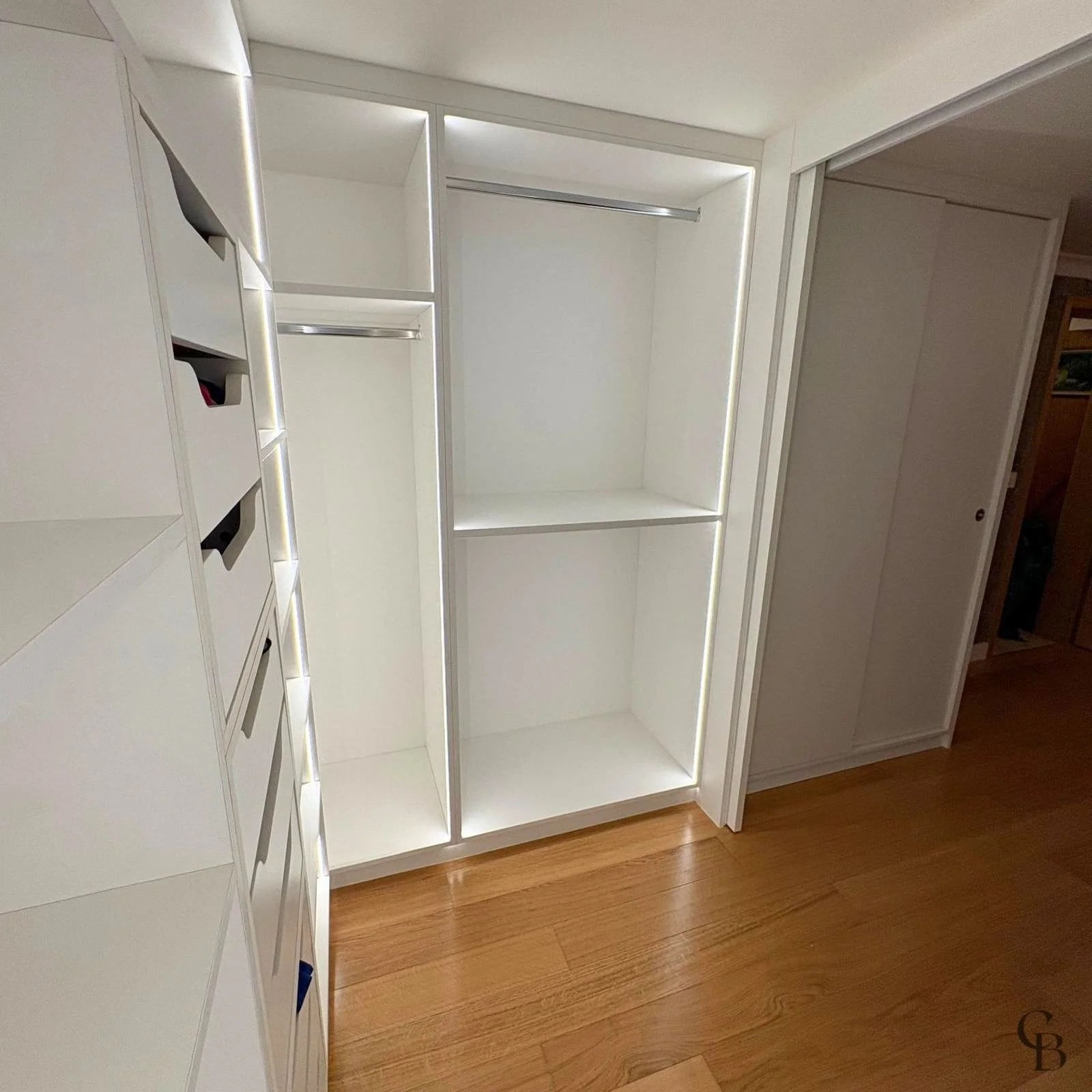 Dressing sur mesure en L avec éclairage LED, penderies et rangements personnalisés réalisés pour optimiser un espace de chambre à Genève.