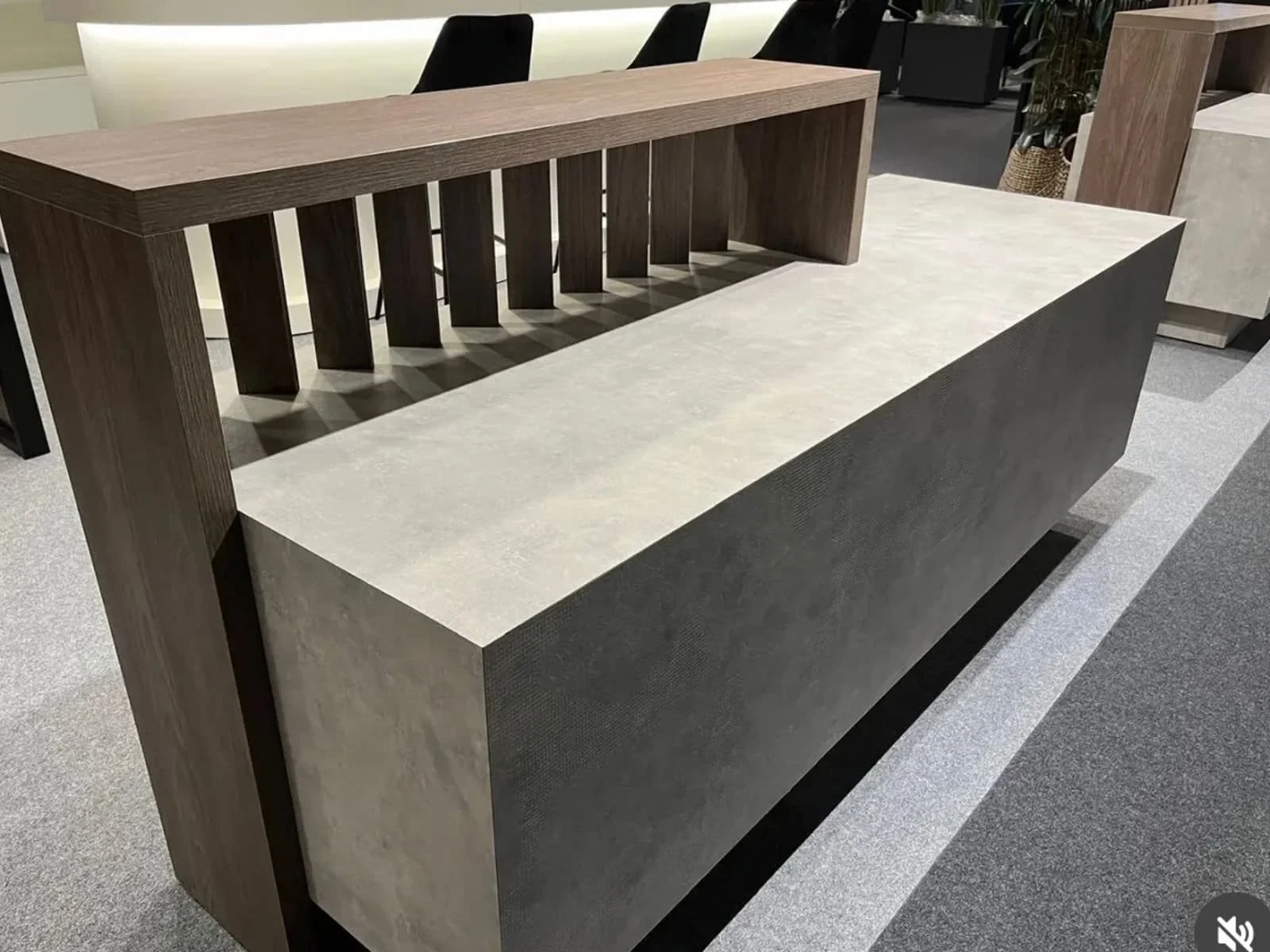 Mobilier professionnel sur mesure présenté à Palexpo Genève, associant un effet béton brut et des lames en bois ajourées pour un design contemporain et élégant.