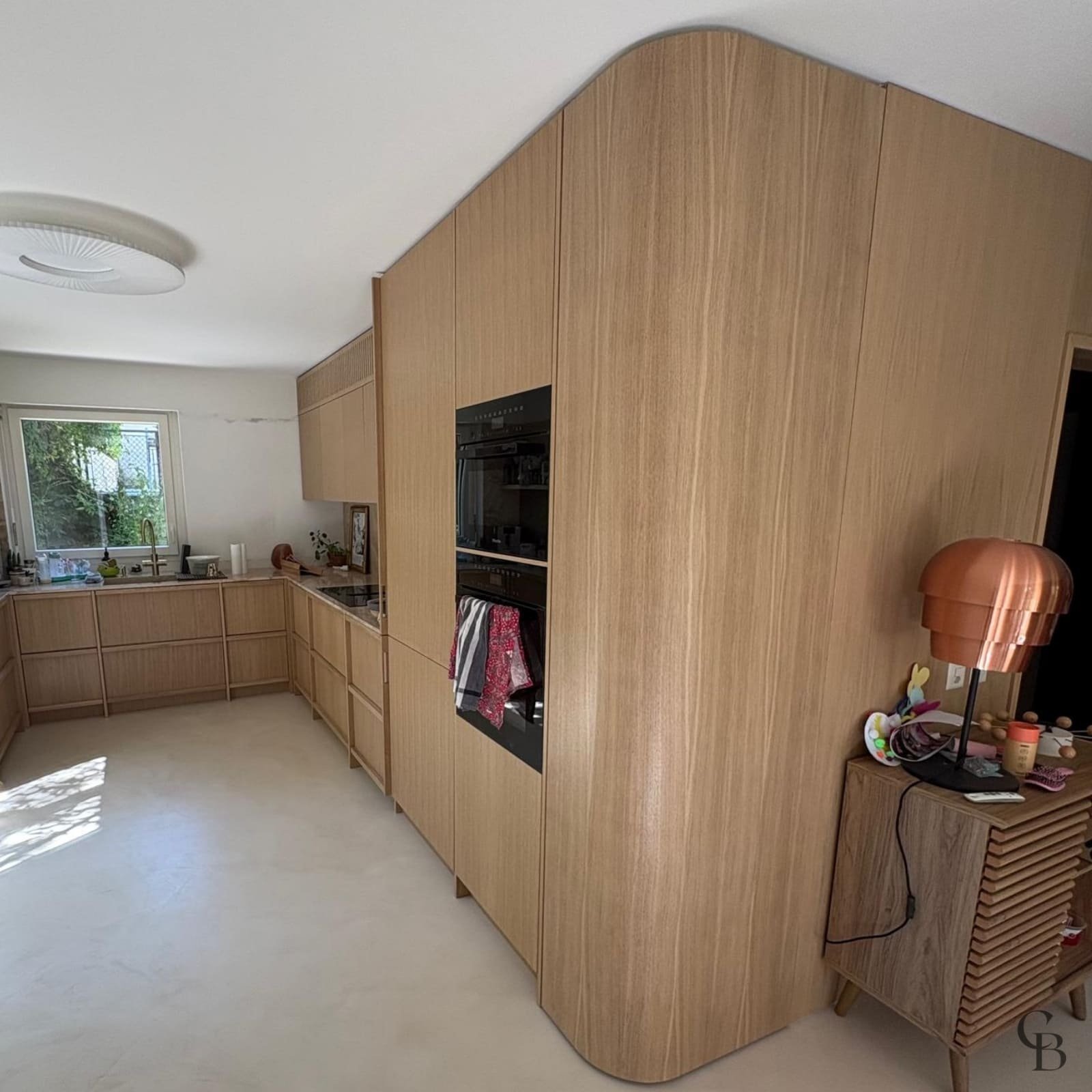 Cuisine ouverte sur la pièce de vie avec rangements toute hauteur réalisée à Nyon par Concept & Bois