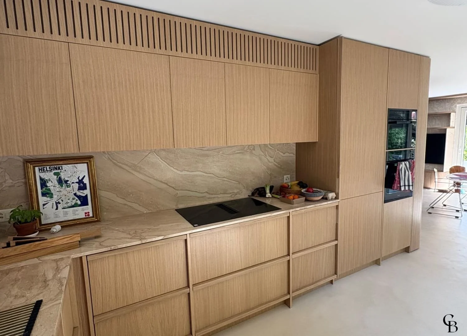 Cuisine sur mesure en chêne naturel avec façades épurées, plans de travail en pierre et finitions haut de gamme.